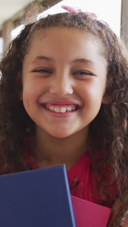 Video-of-happy-biracial-girl-standing-on-school-corridor