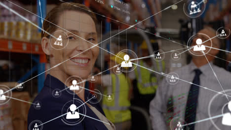 Animation-of-profile-icons-connected-with-lines-over-smiling-caucasian-woman-standing-in-warehouse