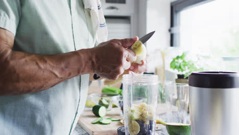 Glücklicher-älterer-Mann-Mit-Gemischter-Abstammung-Bereitet-In-Der-Küche-Gesundes-Getränk-Zu