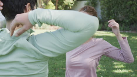 Happy-caucasian-lesbian-couple-stretching-in-sunny-garden,-slow-motion