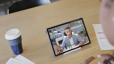 Caucasian-businesswoman-on-tablet-video-call-with-caucasian-male-colleague-on-screen