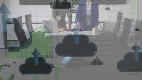 Animation-of-cloud-upload-icons-floating-over-diverse-man-and-woman-discussing-over-a-plan-at-office