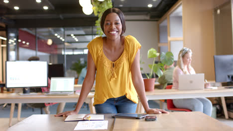 Portrait-of-happy-african-american-casual-businesswoman-standing-in-office-smiling,-slow-motion