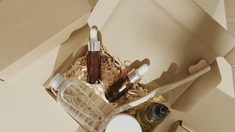 Close-up-of-cardboard-boxes-with-glass-bottles,-cream-tub-and-toothbrush-on-beige-background
