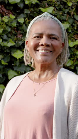 Porträt-Einer-Glücklichen-Afroamerikanischen-Seniorin,-Die-Im-Sonnigen-Garten-Steht-Und-Lächelt,-Zeitlupe