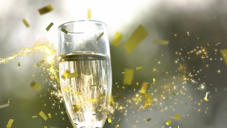 Animation-of-shooting-stars-and-confetti-falling-over-close-up-of-hand-holding-a-champagne-glass