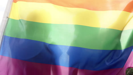 Diverse-gay-male-couple-holding-rainbow-lgbt-flag,-in-slow-motion