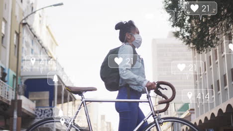 Animation-of-social-media-text-and-icons-over-biracial-woman-in-face-mask-with-bike-in-city
