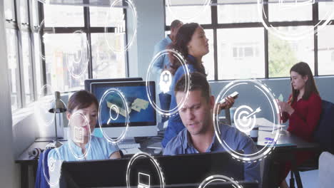 Animation-of-interface-with-multiple-digital-icons-over-diverse-man-and-woman-discussing-at-office