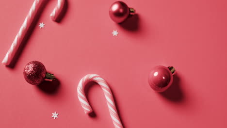 Video-of-baubles-and-candy-canes-christmas-decorations-with-copy-space-on-red-background