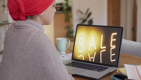 Biracial-Frau-Am-Tisch-Mit-Laptop,-Online-Shopping-Während-Des-Verkaufs,-Zeitlupe