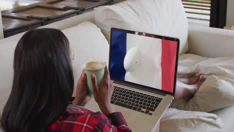 Biracial-woman-watching-laptop-with-rugby-ball-on-flag-of-france-on-screen
