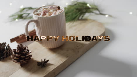 Happy-holidays-text-in-gold-over-christmas-hot-chocolate-with-marshmallows-on-white-background