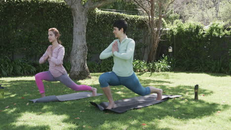 Glückliches-Kaukasisches-Lesbisches-Paar-Praktiziert-Yoga-Im-Sonnigen-Garten,-Zeitlupe