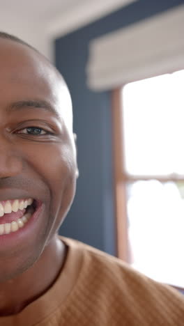 Vertical-video-of-portrait-of-happy-african-american-man-smiling-at-home,-slow-motion