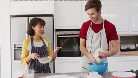 Video-of-happy-diverse-couple-baking-together-in-kitchen