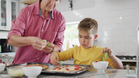 Glücklicher-Kaukasischer-Großvater-Und-Enkel-Machen-Pizza-In-Der-Küche,-Zeitlupe