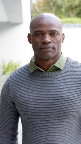 Portrait-of-happy-african-american-man-standing-and-laughing-in-front-of-house,slow-motion