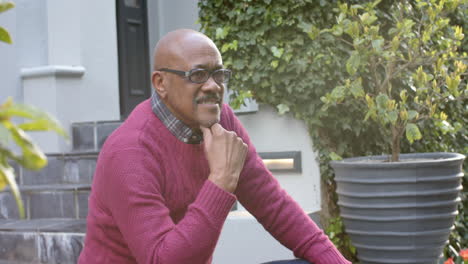 Happy-senior-african-american-man-in-glasses-sitting-and-laughing-in-garden,-slow-motion
