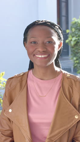 Portrait-of-happy-african-american-woman-standing-and-smiling-in-front-of-house,slow-motion