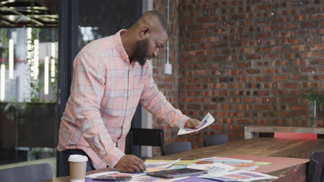 African-american-male-creative-looking-at-designs-in-office,-slow-motion