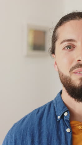Vertical-video-of-half-face-of-happy-caucasian-man-with-beard-standing-and-smiling-on-sunny-house