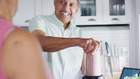 Glückliches-älteres-Biracial-Paar-Bereitet-Gesundes-Getränk-In-Der-Küche-Zu