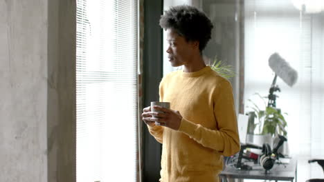 Hombre-Afroamericano-Pensativo-Tomando-Café-Y-Mirando-Por-La-Ventana-En-Casa,-Cámara-Lenta