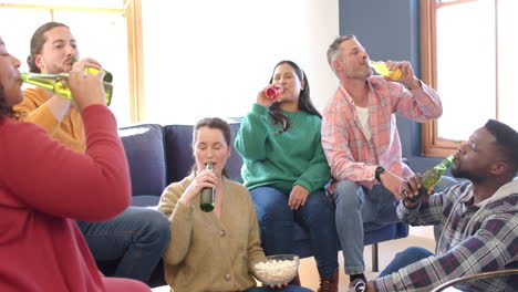 Happy-diverse-male-and-female-friends-relaxing-at-home-together-and-drinking-beers
