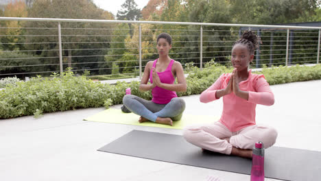 Glückliche-Afroamerikanische-Tochter-Und-Mutter-Praktizieren-Yoga-Im-Sonnigen-Garten,-Zeitlupe