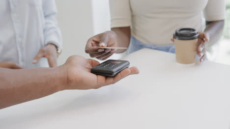 Midsection-of-african-american-woman-making-contactless-card-payment-for-coffee-in-cafe,-slow-motion