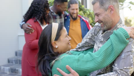 Happy-diverse-friends-with-flags-welcoming-home-male-soldier-friend