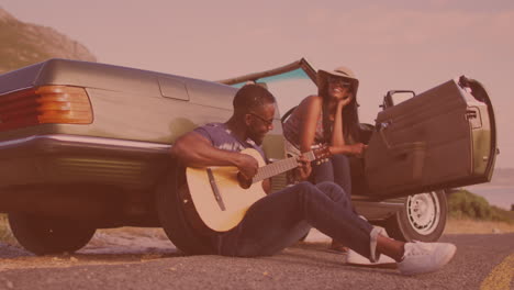Hombre-Afroamericano-Tocando-La-Guitarra-Para-Su-Esposa-Cerca-Del-Auto-En-La-Calle