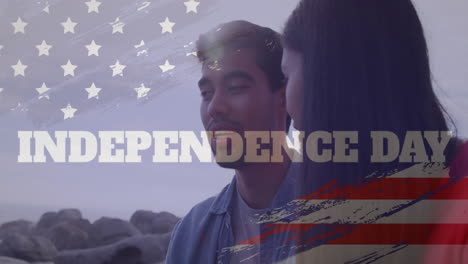 Animation-Des-USA-Flaggeneffekts-Und-Des-Textes-Zum-Unabhängigkeitstag-Vor-Einem-Gemischtrassigen-Paar,-Das-Sich-Am-Strand-Unterhält