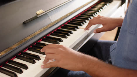 Mid-section-of-biracial-man-playing-piano-at-home,-slow-motion