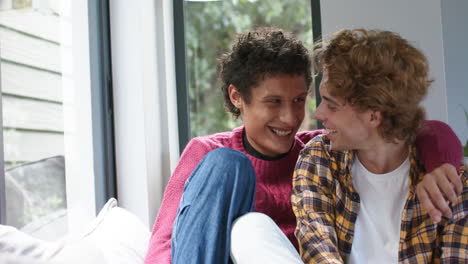 Portrait-of-happy-diverse-gay-male-couple-embracing-and-smiling-at-home,-slow-motion