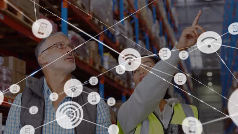Animation-of-network-of-connections-with-icons-over-diverse-people-working-in-warehouse