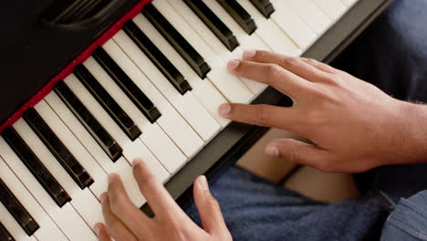 Close-up-of-hands-of-biracial-man-playing-piano-at-home,-slow-motion
