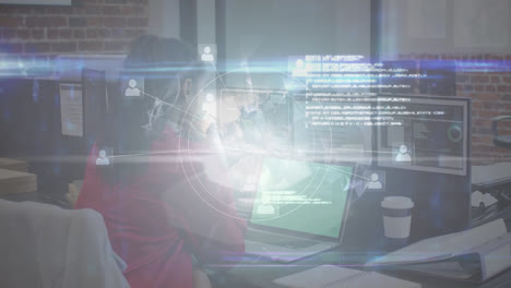 Animation-of-digital-screen-with-globe-over-biracial-woman-using-laptop-in-office