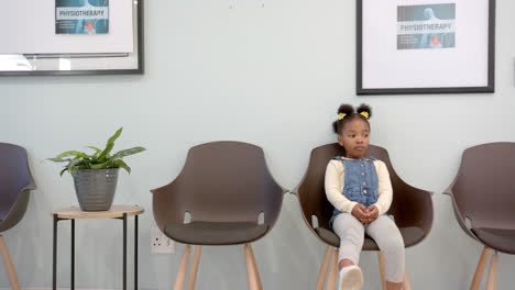African-american-girl-sitting-in-hospital-waiting-room-with-copy-space,-slow-motion