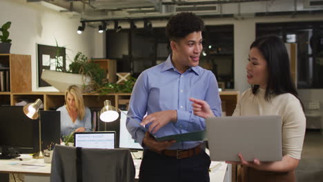 Biracial-man-and-Asian-woman-discuss-business-work-in-an-office