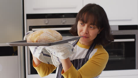 Video-Einer-Glücklichen-Asiatischen-Frau,-Die-Einen-Kuchen-Aus-Dem-Ofen-Nimmt