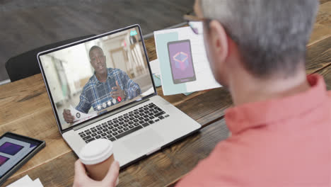 Caucasian-businessman-on-laptop-video-call-with-african-american-male-colleague-on-screen
