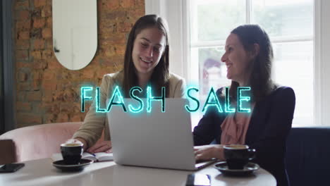 Animation-of-flash-sale-text-over-diverse-businesswomen-using-laptop