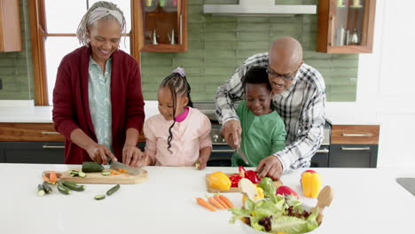 Glückliche-Afroamerikanische-Großeltern-Und-Enkelkinder-Beim-Gemüsehacken-In-Der-Küche,-Zeitlupe