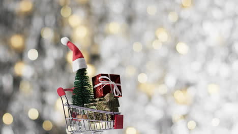 Video-of-shopping-trolley-with-christmas-tree-and-gifts-and-copy-space-on-fairy-lights-background