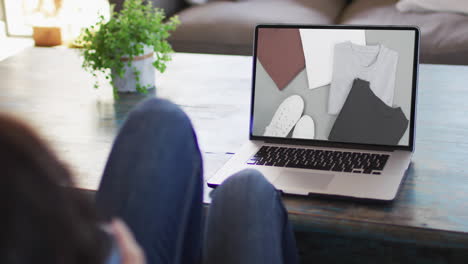 Knees-of-woman-at-table-using-laptop,-online-shopping-for-clothes,-slow-motion