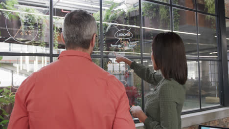 Diverse-male-and-female-colleague-brainstorming-on-glass-wall-in-office,-slow-motion