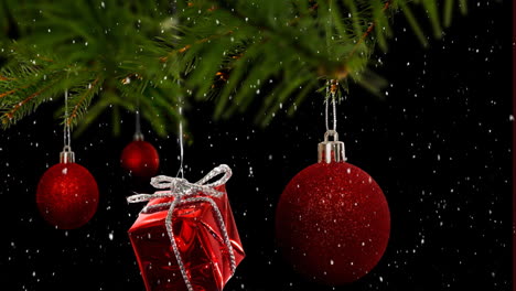 Animation-of-snow-falling-over-hanging-baubles-and-christmas-gifts-on-a-branch-on-black-background