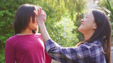 Video-of-happy-asian-mother-and-daughter-having-fun-in-garden